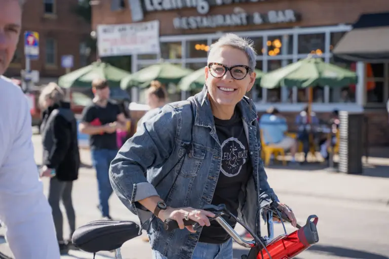 Person smiling on a bike with Leaning Tower of Pizza in the background